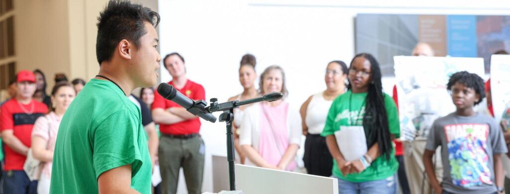 A student speaks into a microphone to an audience